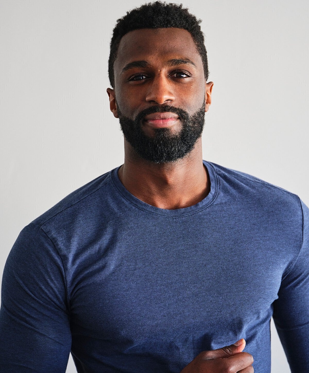 Smiling man in blue shirt against white background.