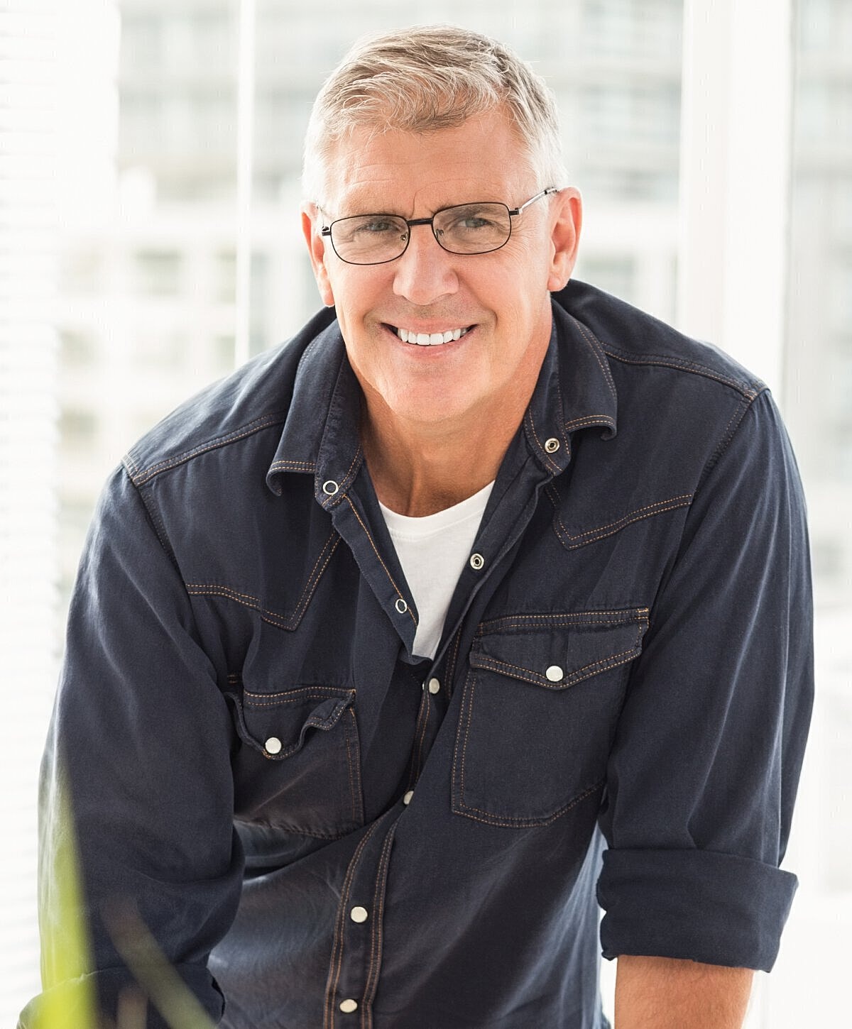Smiling man wearing glasses indoors, looking friendly.
