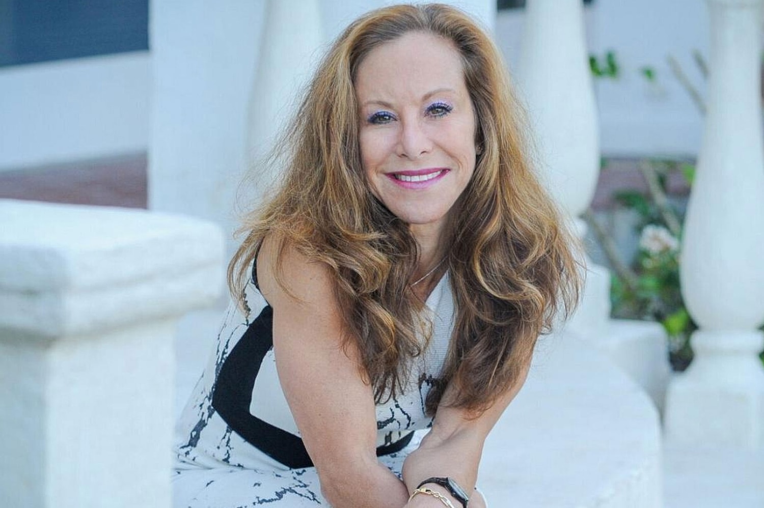 Woman sitting on steps, smiling confidently.