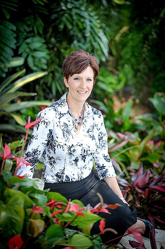 Woman sitting among vibrant tropical plants.