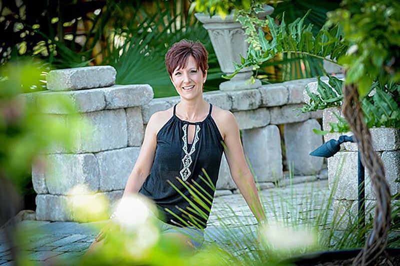 Woman smiling in a garden setting.