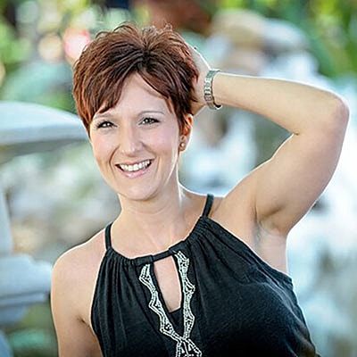 Smiling woman outdoors with short, styled hair.