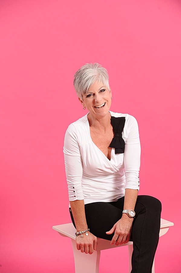 Woman smiling in front of pink background.