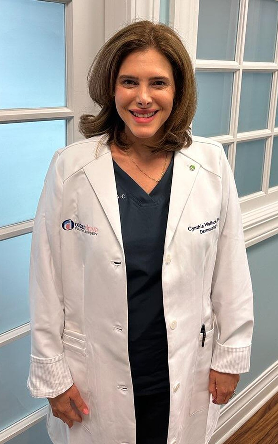 Smiling man in blue suit against plain background.