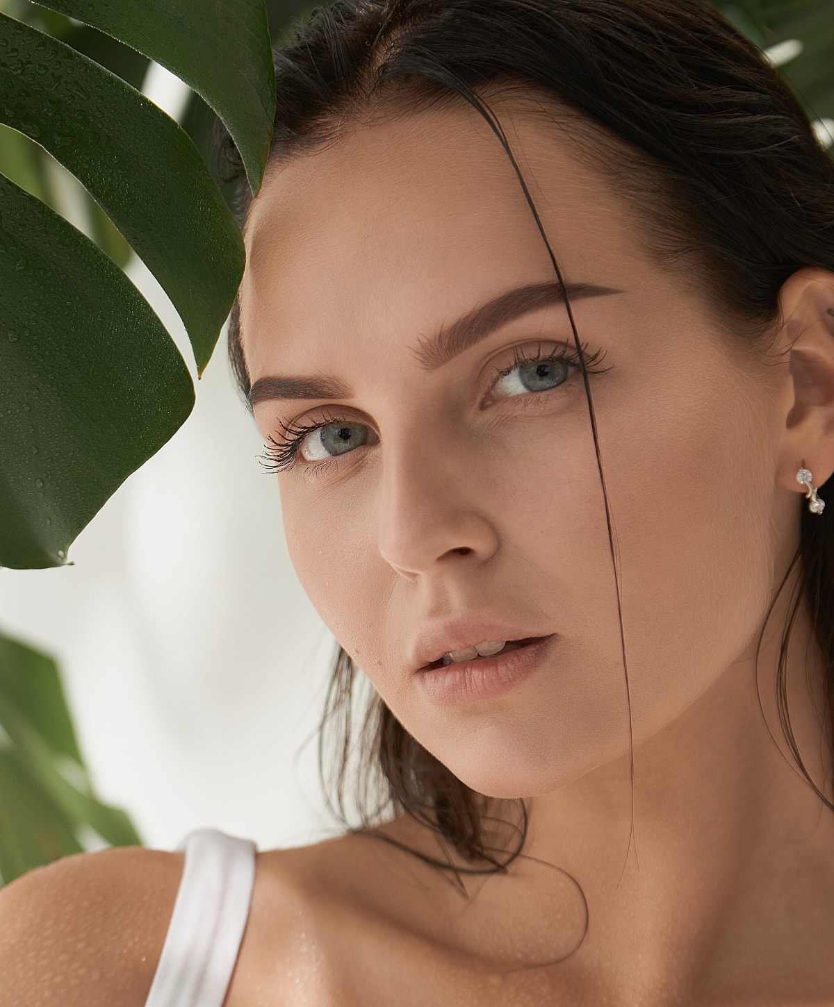 Woman with natural makeup, surrounded by greenery.