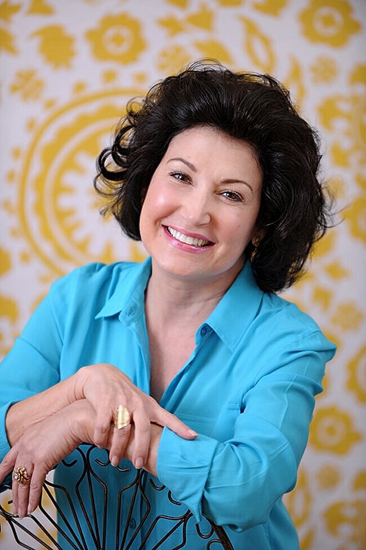 Woman smiling against a colorful backdrop.