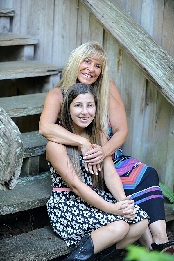 Two women smiling on wooden stairs.