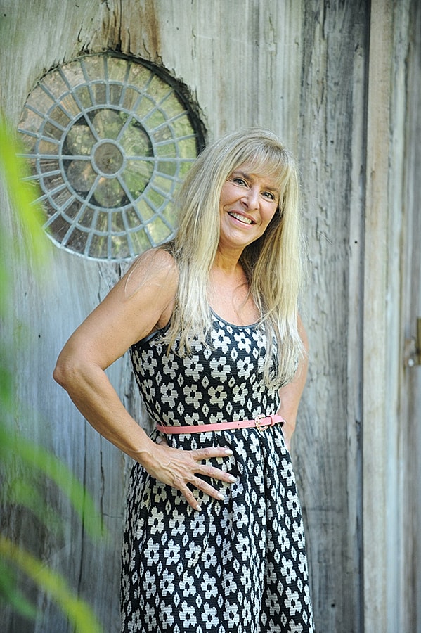 Smiling woman in floral dress by wooden door.