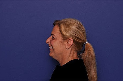 Woman smiling against a blue background.