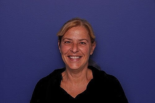 Smiling woman against a purple background.