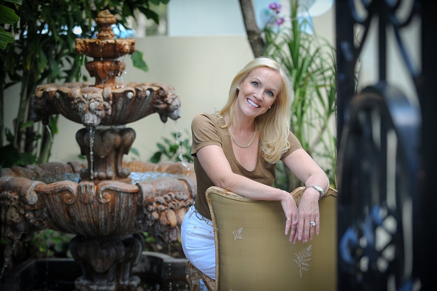 Smiling woman by ornate fountain outdoors.