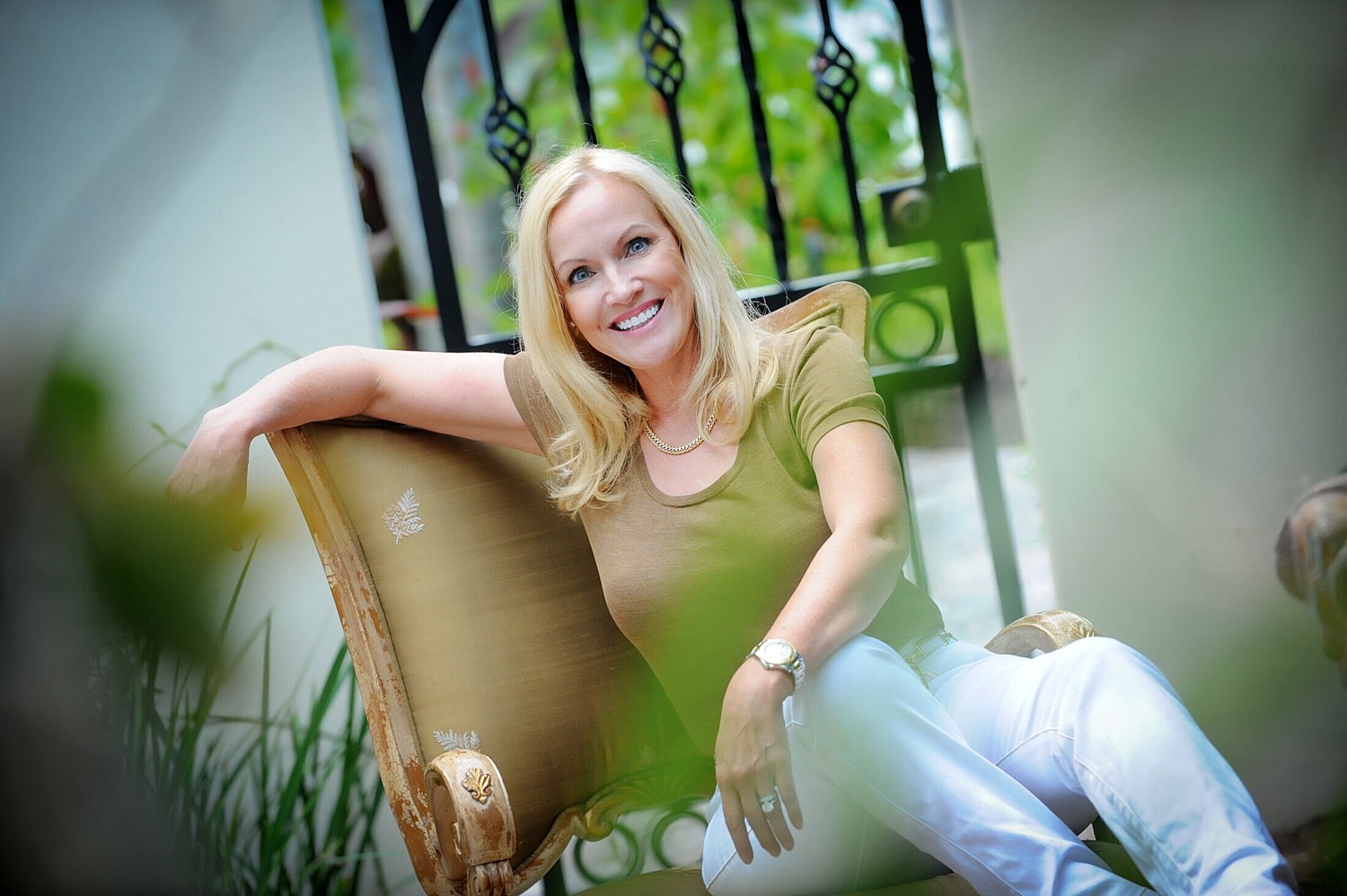 Smiling woman sitting casually in outdoor setting.