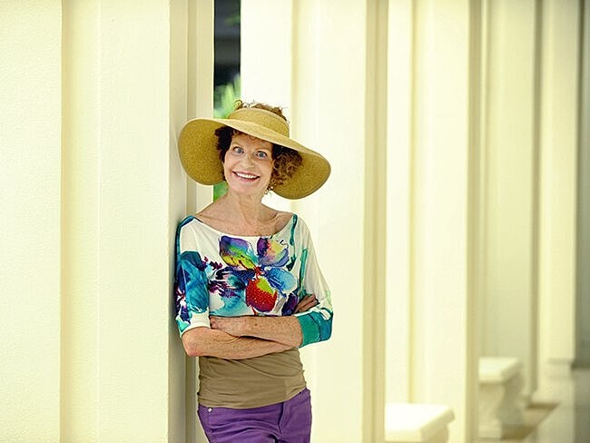 Smiling woman in hat against modern architecture.