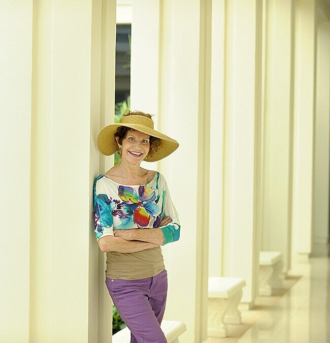 Smiling woman in colorful outfit against columns.