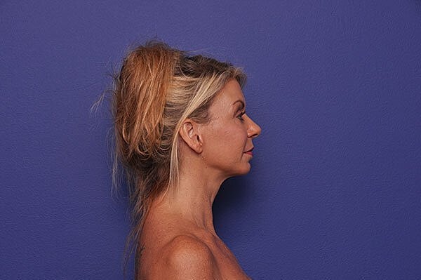 Woman with ponytail against purple background.