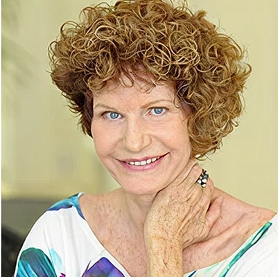 Smiling woman with curly hair and colorful blouse.