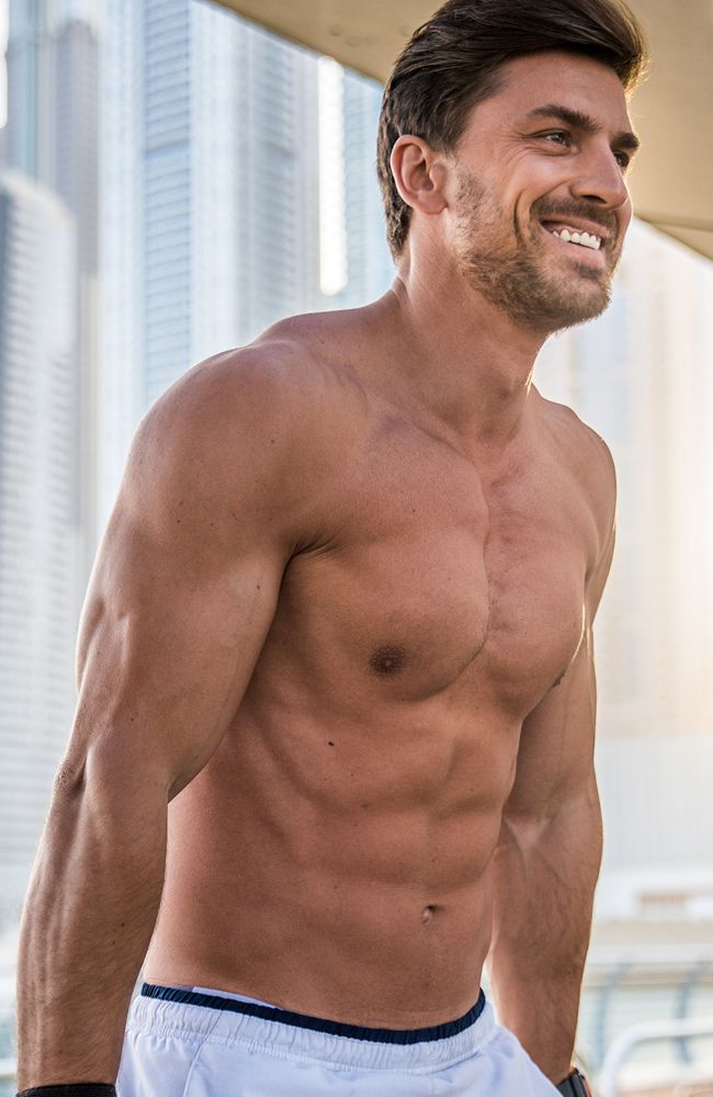Smiling muscular man outdoors in urban setting.