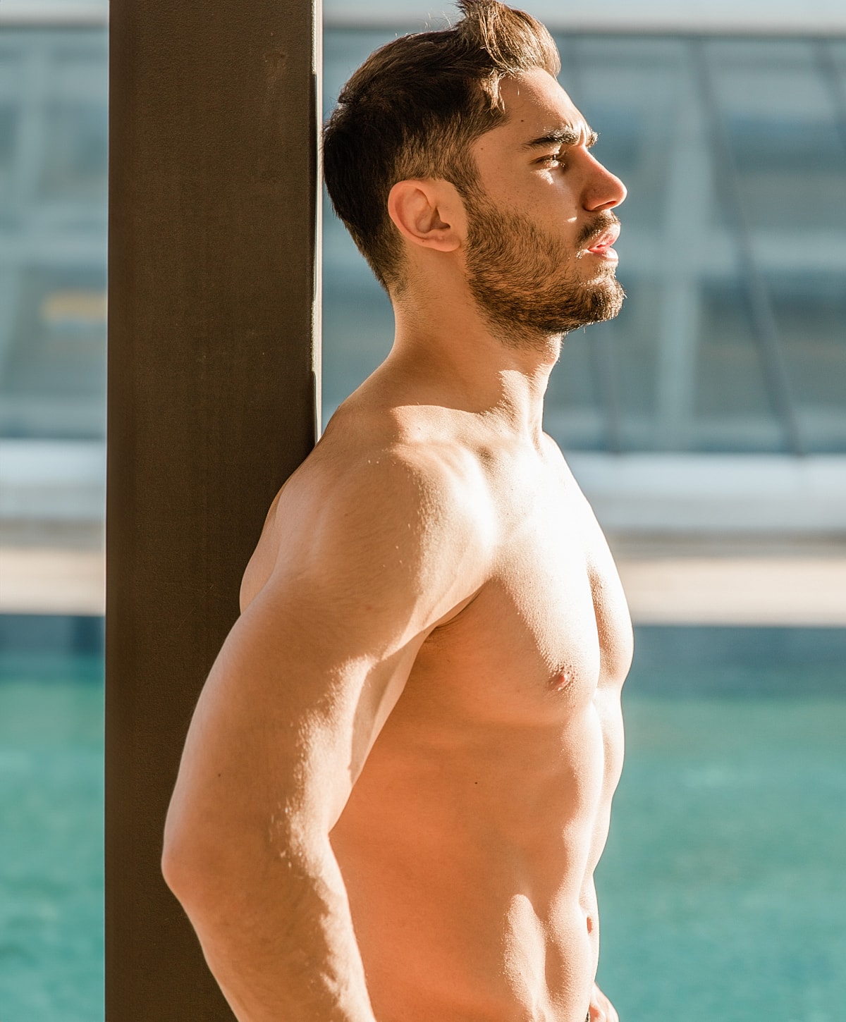 Man leaning against pillar by water.