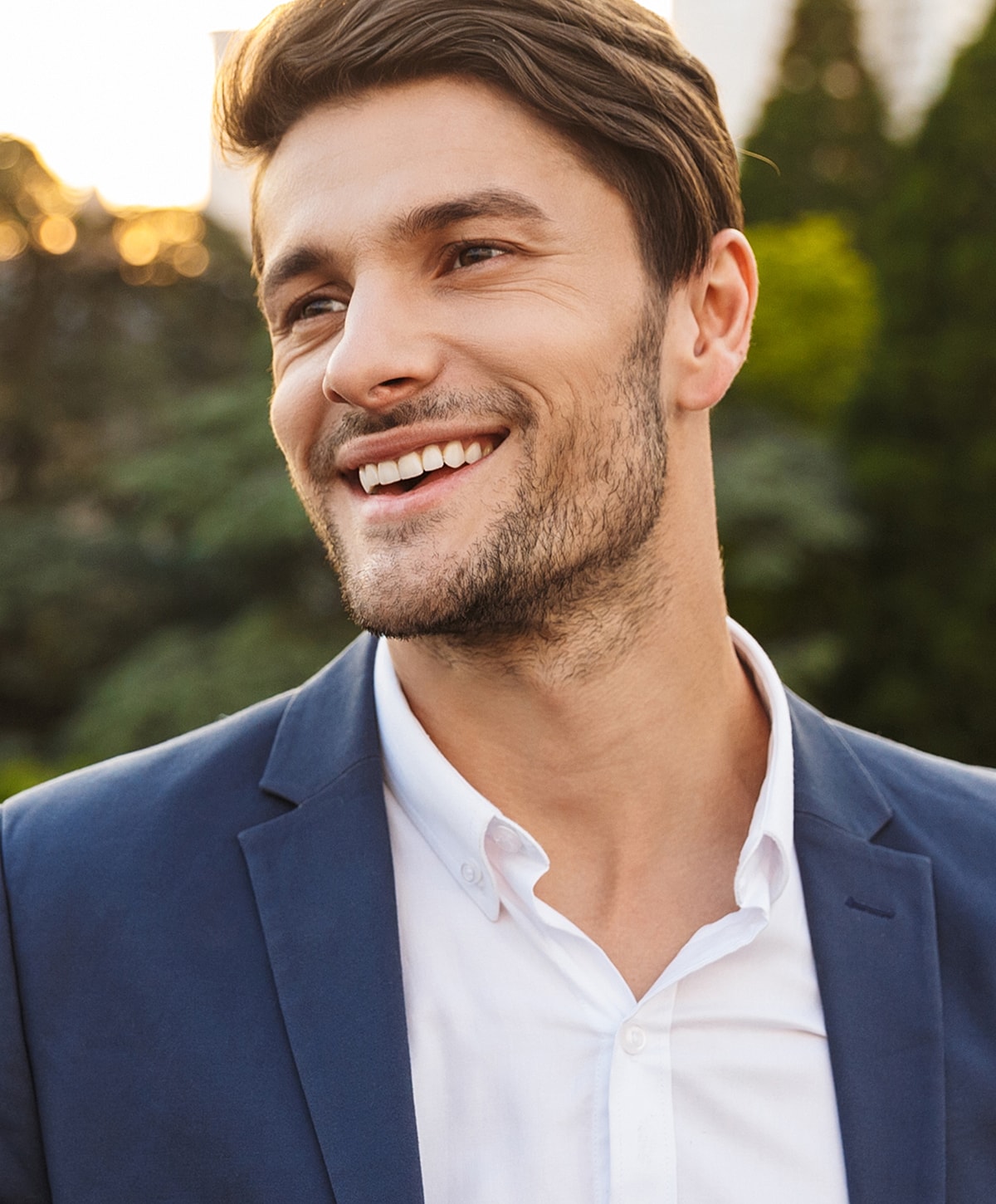 Smiling man in a blue suit outdoors.