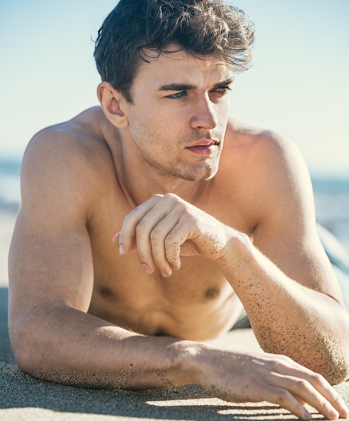 Man lying on sand at the beach.