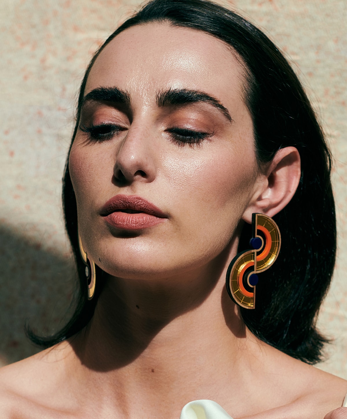 Model wearing bold, colorful statement earrings.