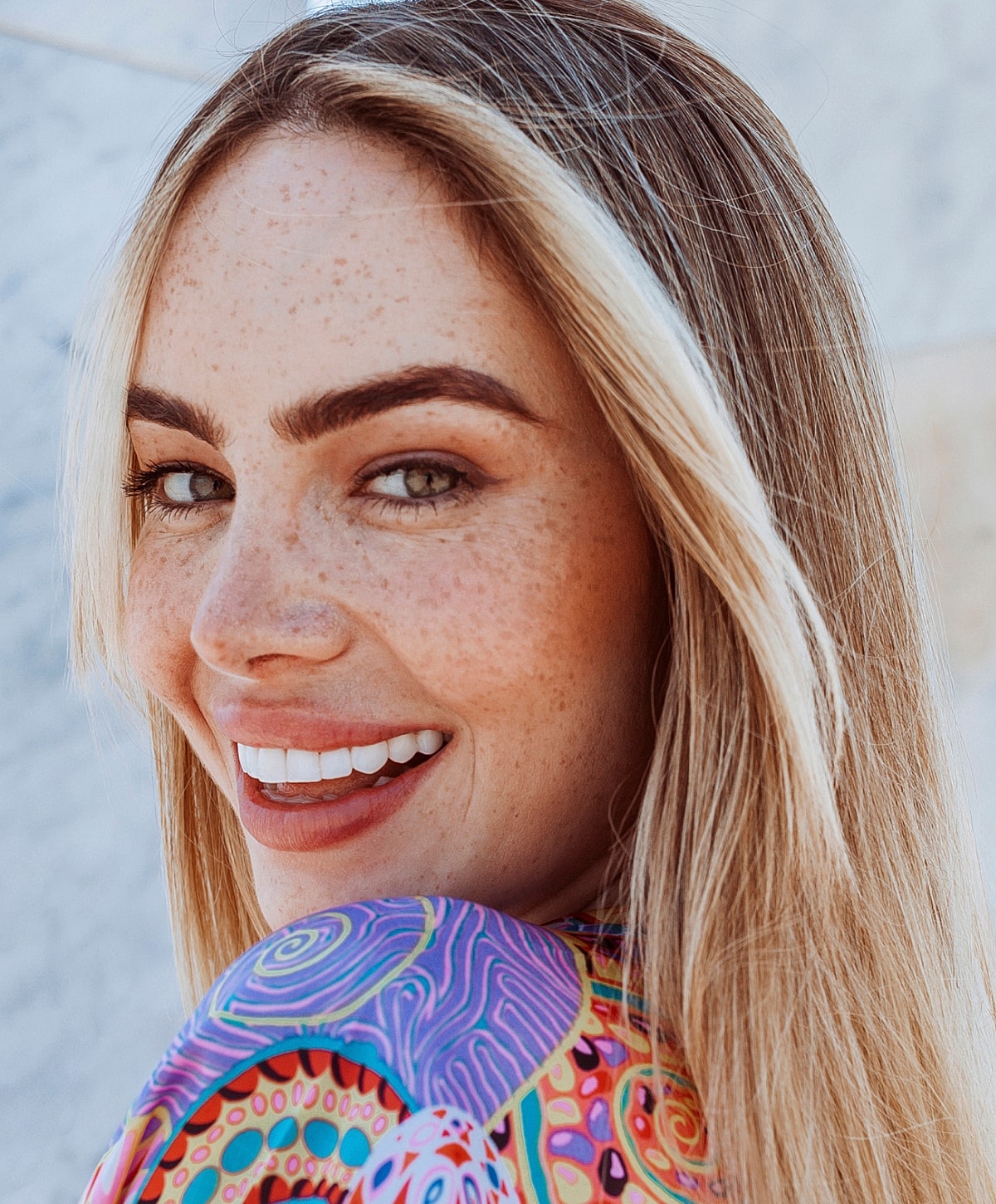 Smiling woman with freckles and colorful shirt.