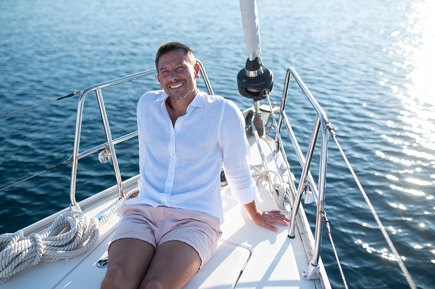 Man relaxing on a sailboat under sunlight.