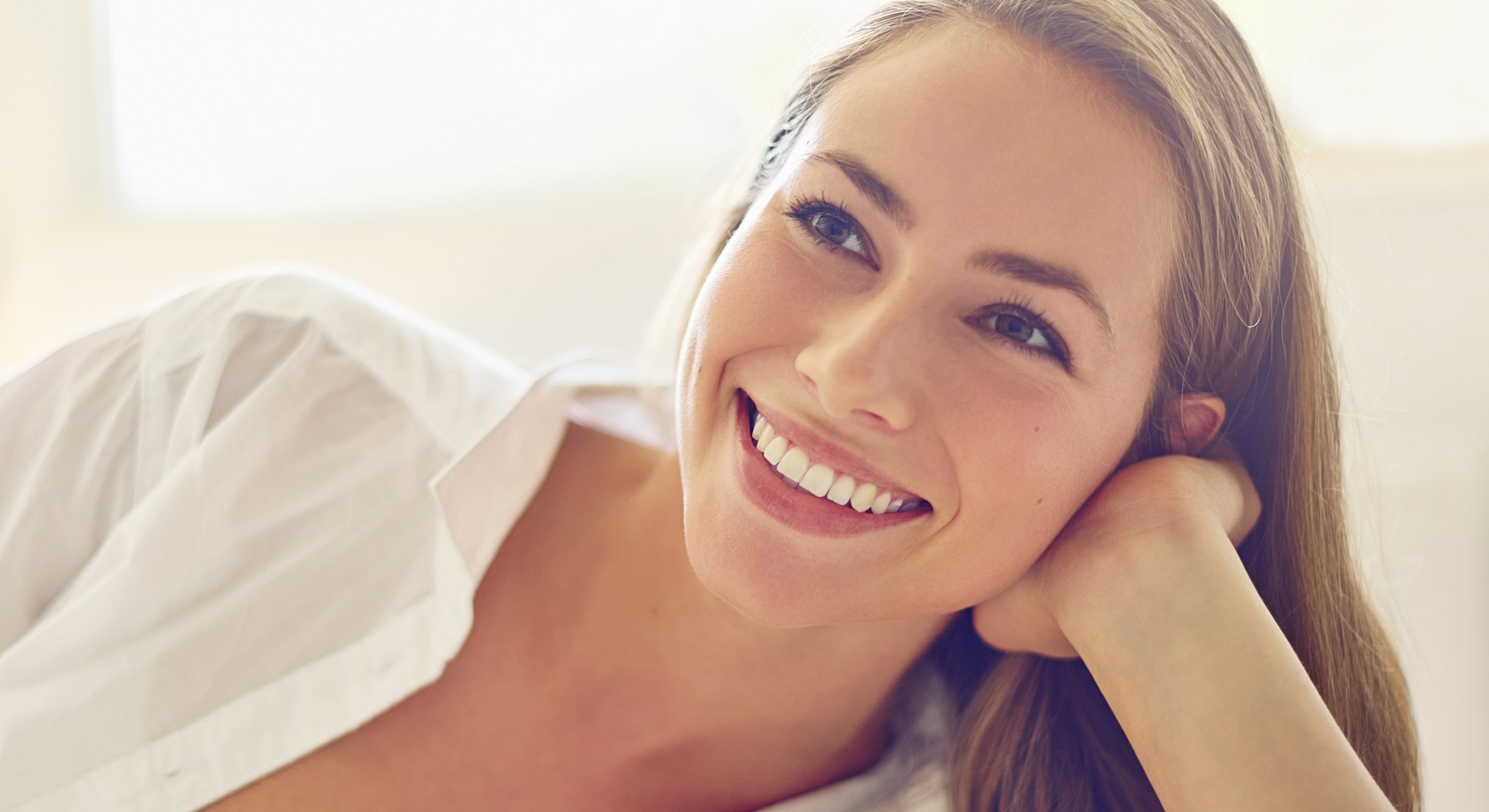 Smiling woman wearing hat and floral blouse.