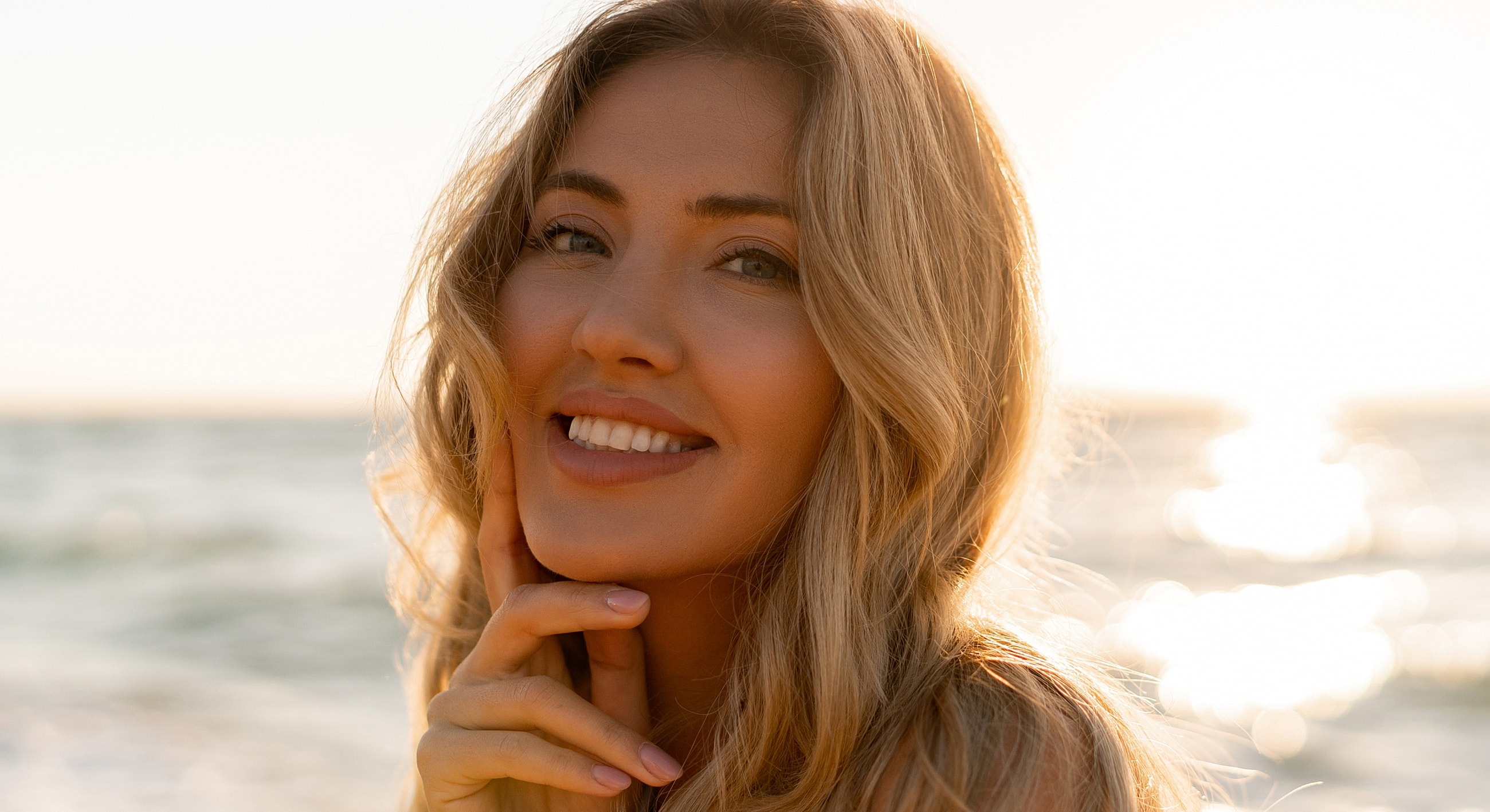 Smiling woman by the beach at sunset.