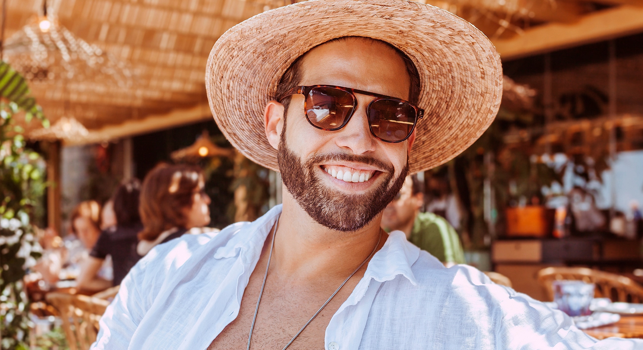 Man smiling in straw hat and sunglasses.
