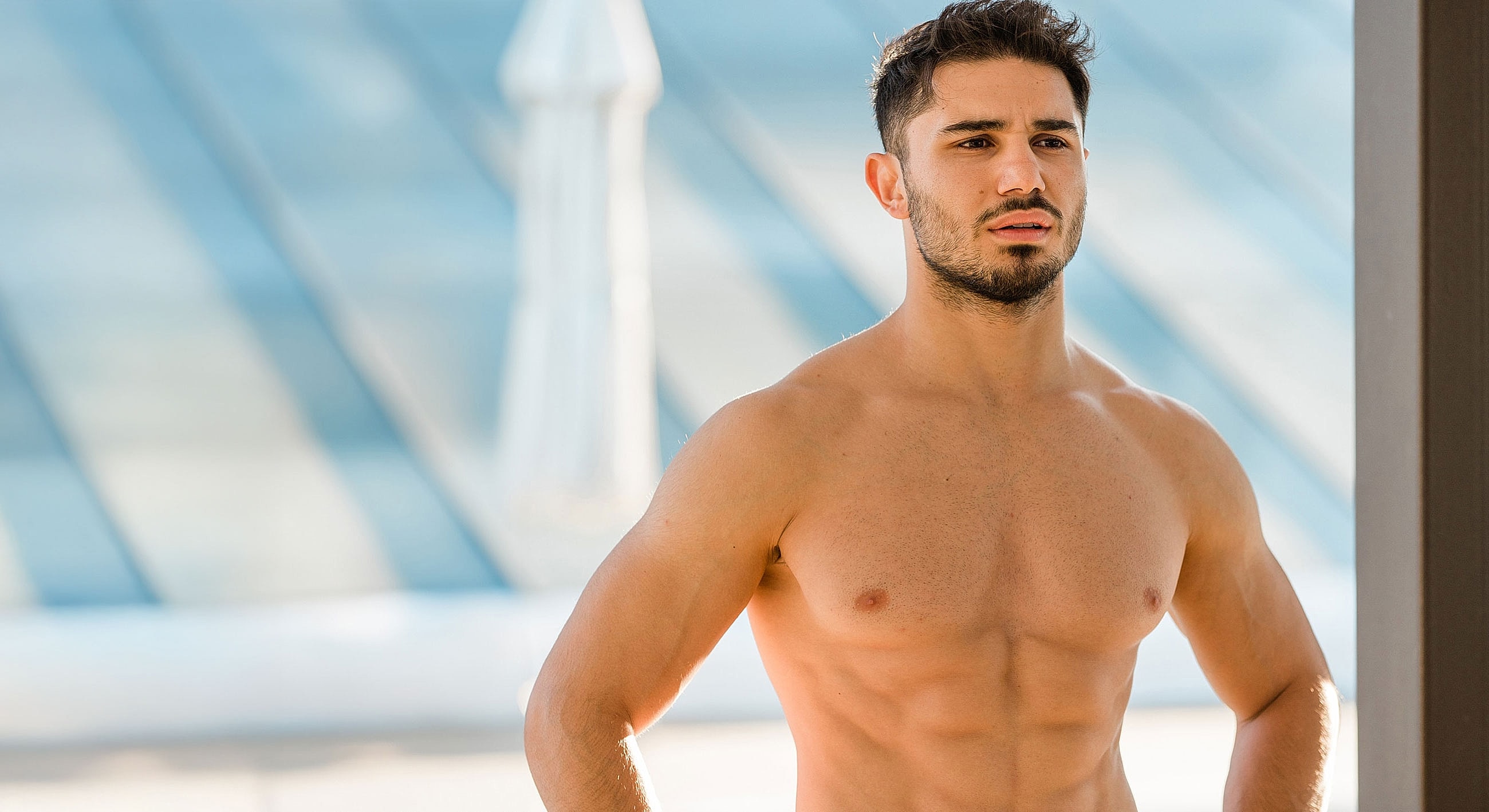 Shirtless man standing outdoors in natural light.
