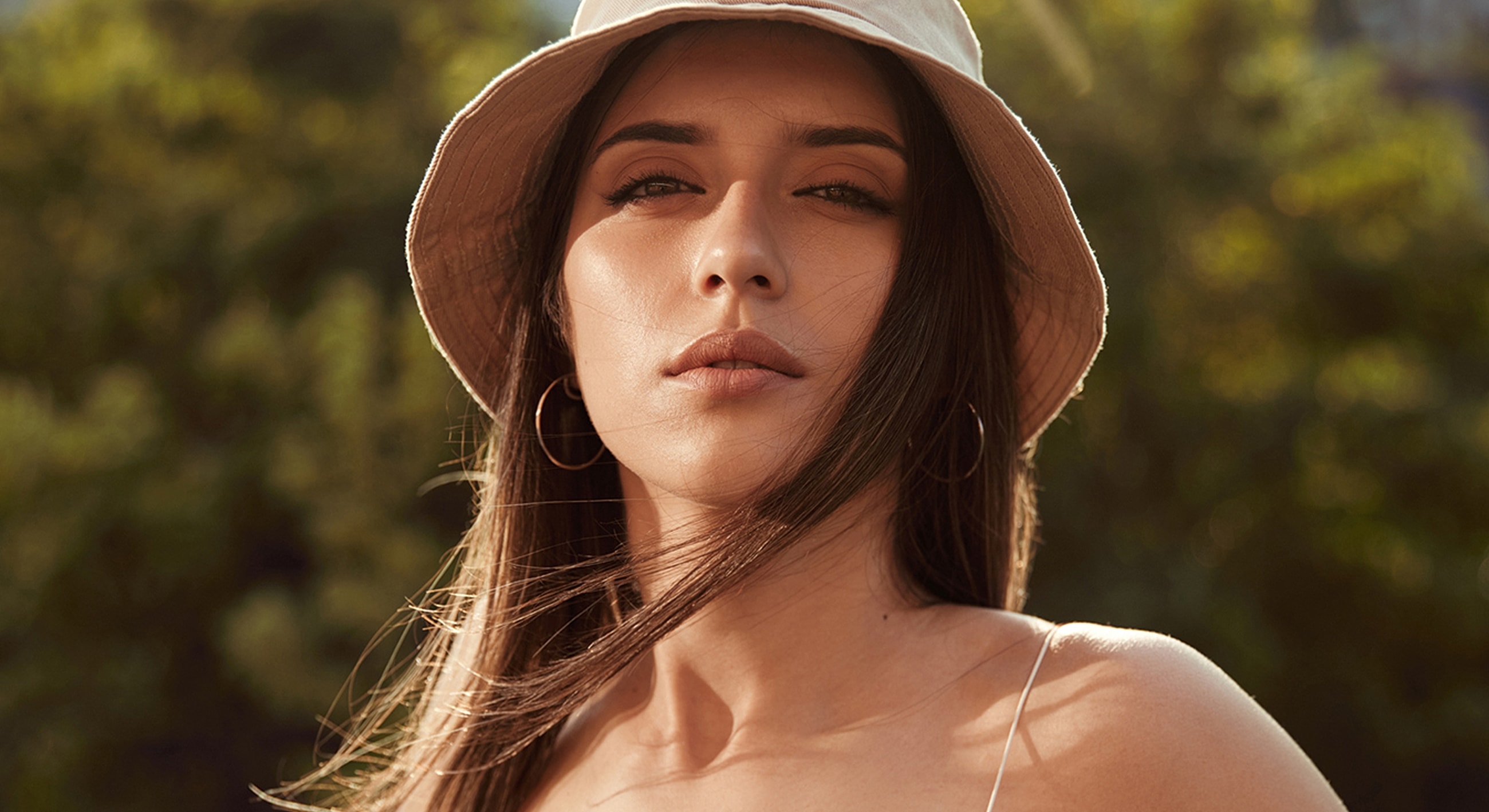 Woman in a hat with flowing hair outdoors.