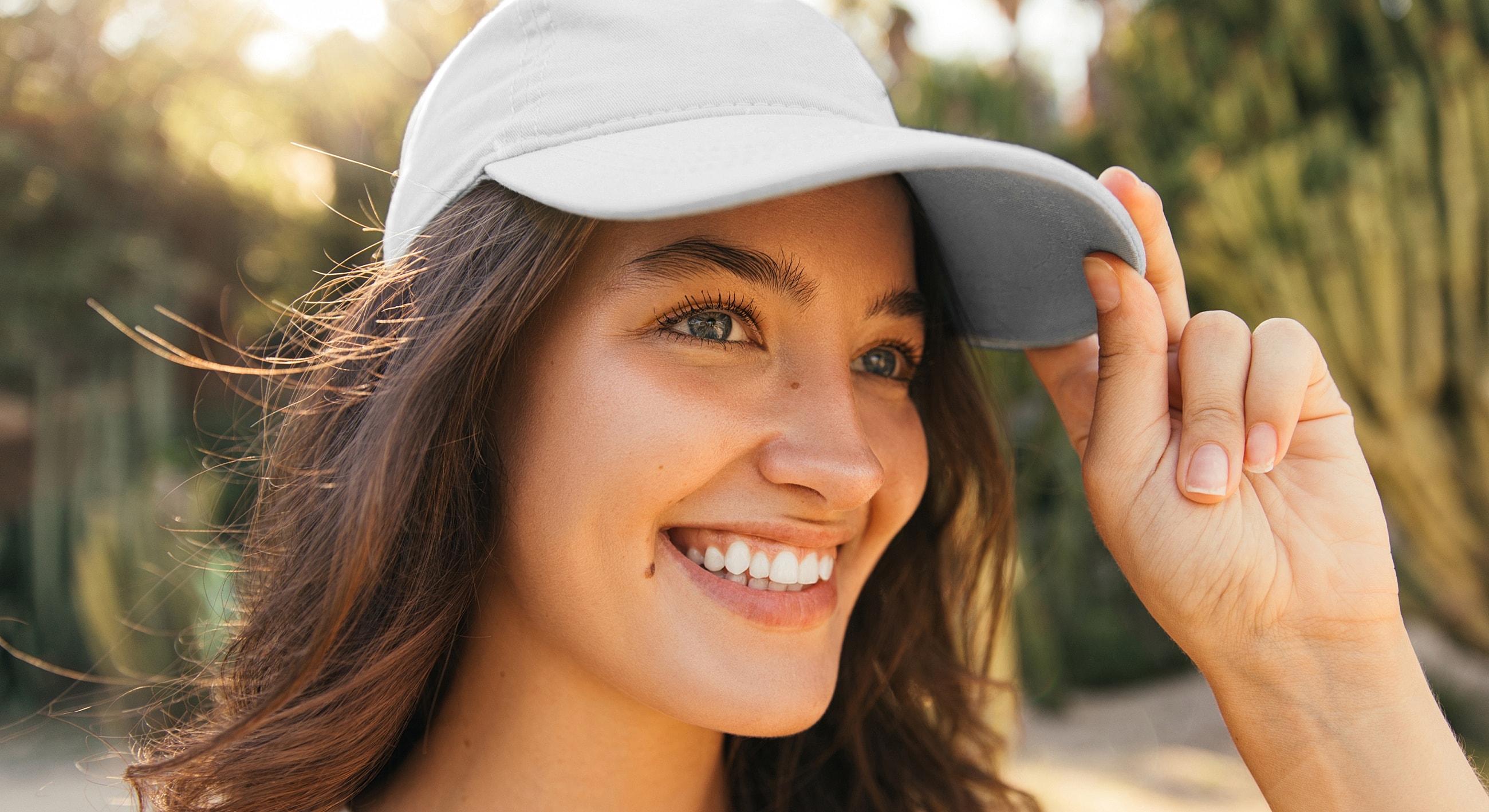 Smiling woman wearing a cap outdoors.